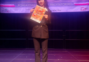 Ula Mruszczyk na scene odbiera II nagrodę w powiatowym konkursie "Strofy dla Niepodlegej"