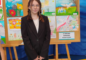 Marianna Składowska stoi przy nagrodzonej drugim miejscem pracy w konkursie plastycznym.