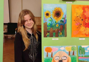 Wiktoria Albrecht stoi przy swojej nagrodzonej pracy plastycznej.