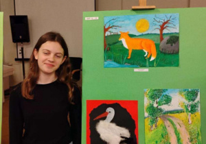 Zuzia Pietrzach stoi przy swojej pracy w konkursie Eko-pocztówka.