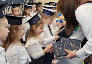 Uczniowie klas pierwszych tuż po pasowaniu otrzymują małe prezenty od wychowawcy i pani dyrektor.