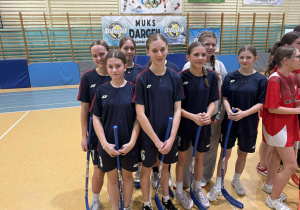 reprezentacja naszych dziewcząt w strojach sportowych szkolnych \ kijami do unihokeja podczas otwarcia zawodów.