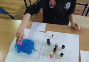 Uczeń wylewa farbę na wodę.