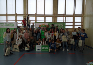 Sala gimnastyczna. Na tle drabinek pozuje duża grupa uczniów. Przed nimi napis "Warsztaty edukacyjne".
